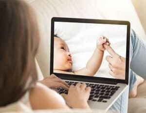 Baby and mother engaging in breastfeeding consultation via laptop.